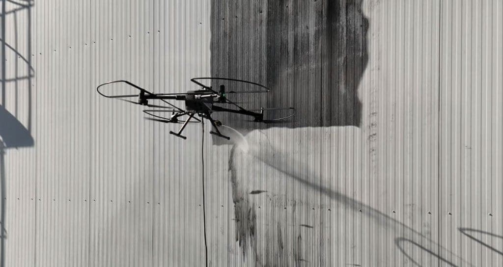 Drone Dronewash limpando a fachada de um edifício comercial