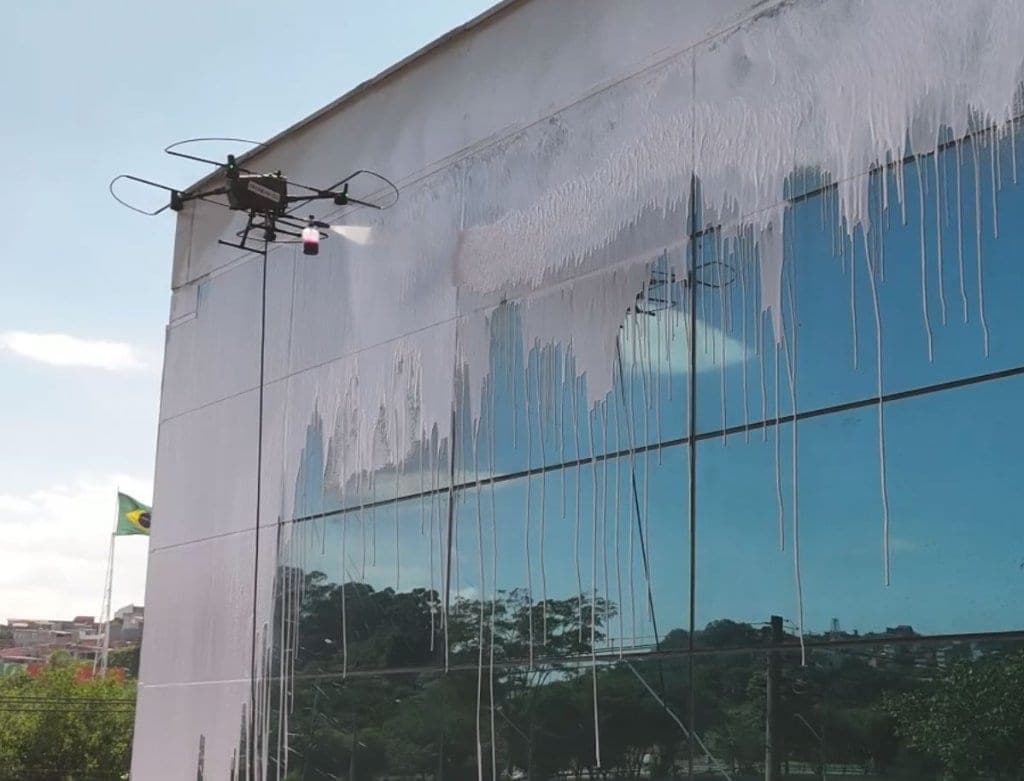 Drone Dronewash limpando fachada envidraçada em altura